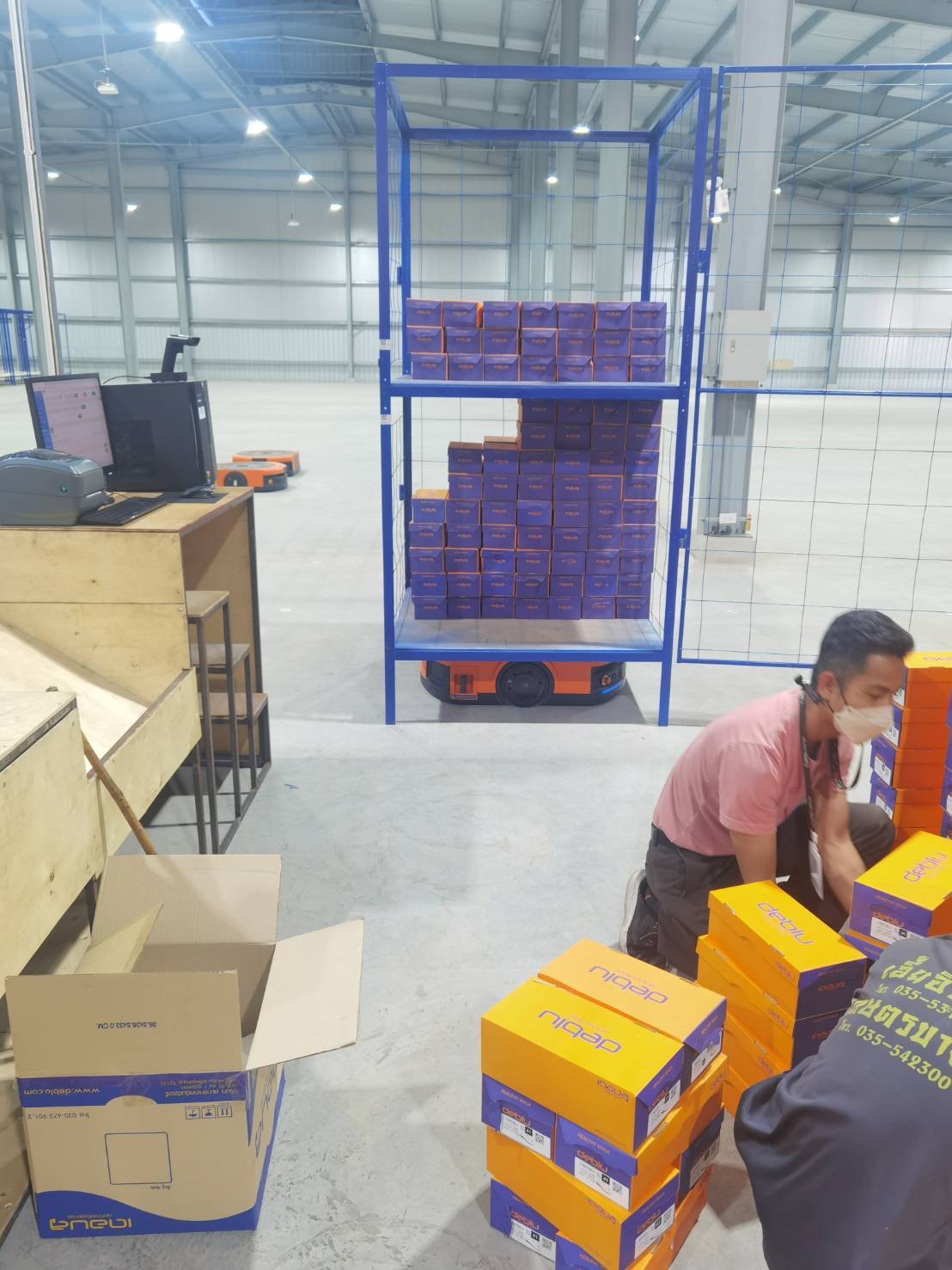 พนักงานหยิบรองเท้าจากชั้นที่ AGV ขนมาให้ — ไม่ต้องเดินไปไหน